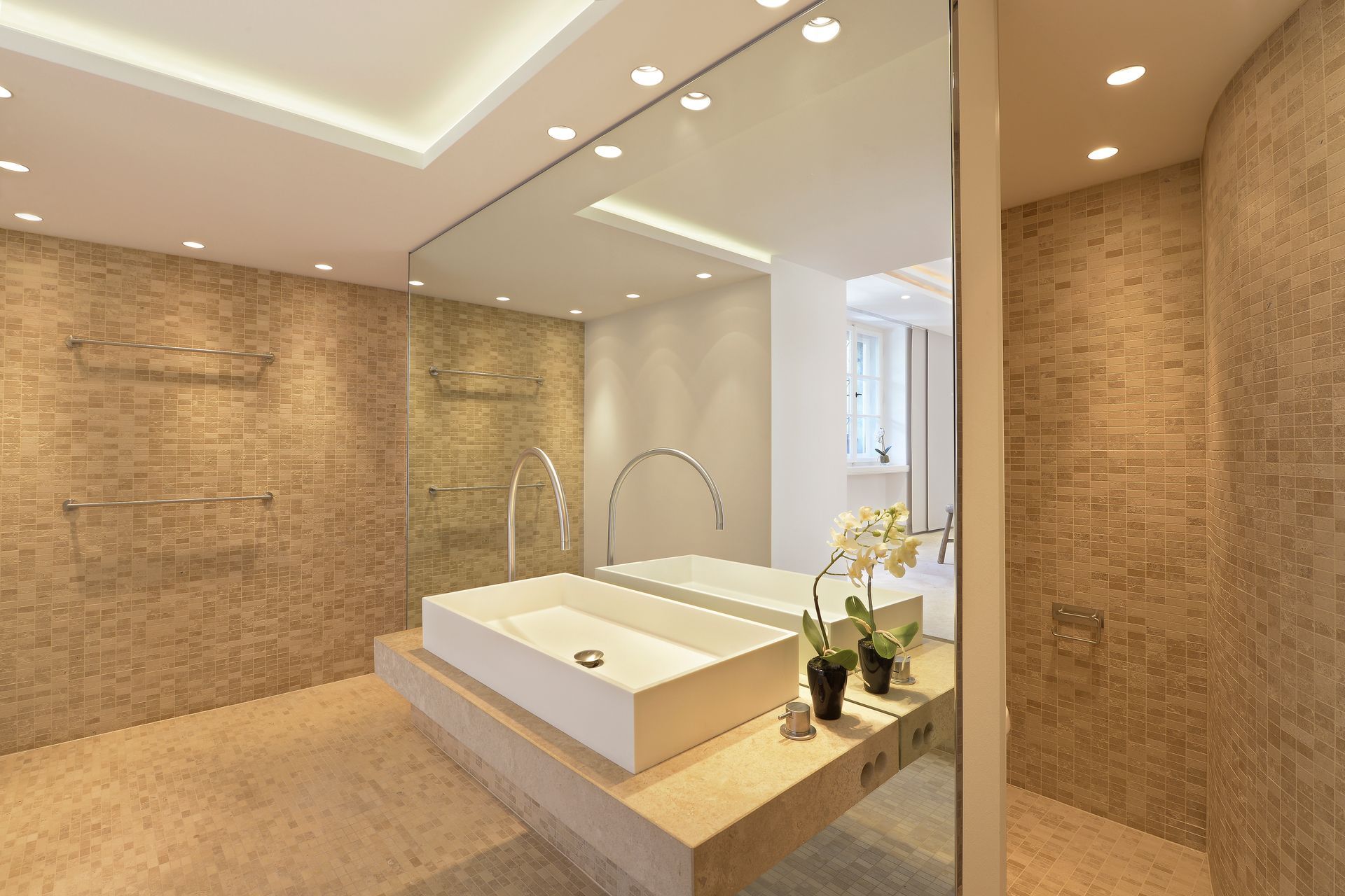 Modern bedroom with a low white bed, warm tan walls, and a minimalist spa-like design.