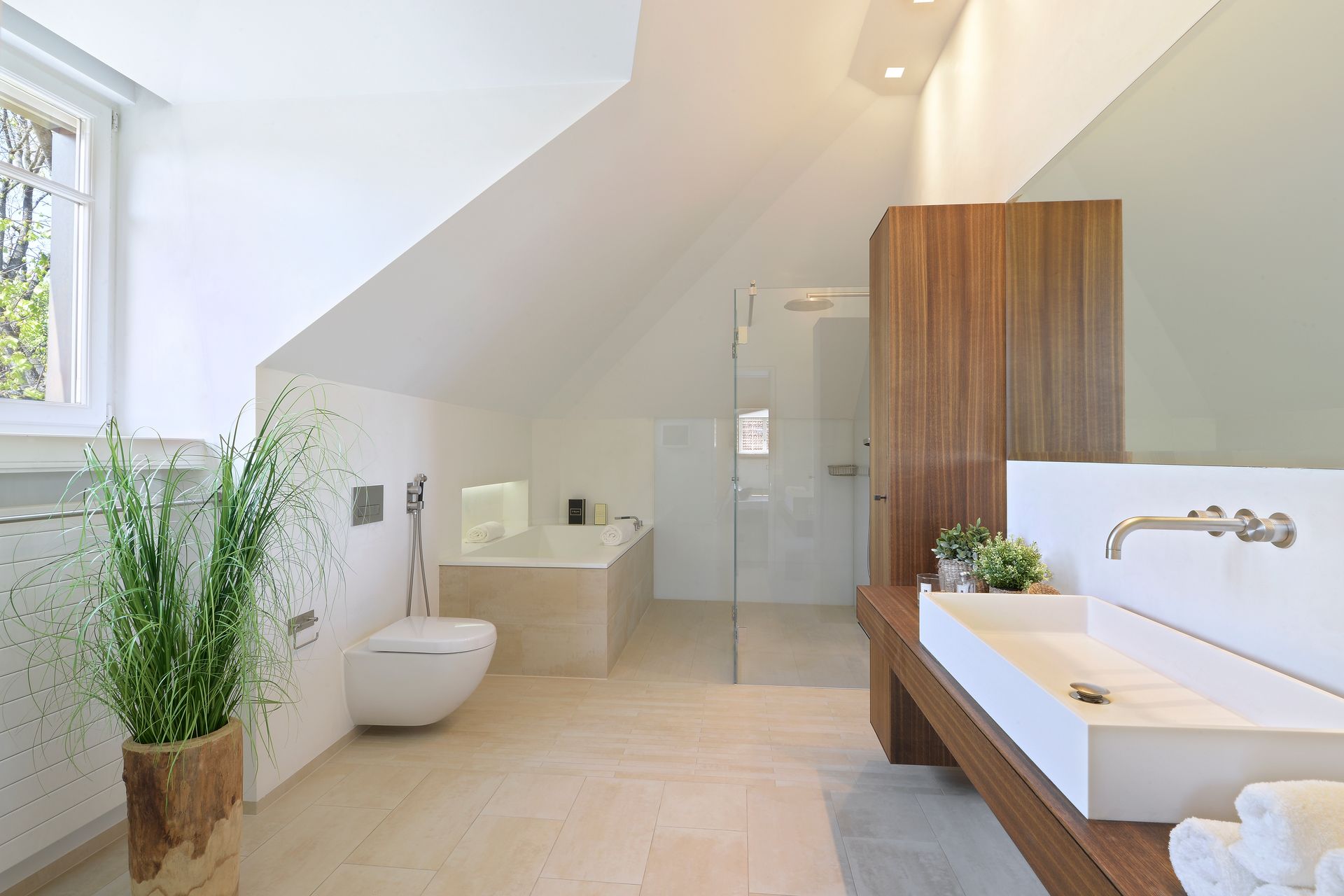 Bright modern bathroom with freestanding tub, sink, wooden vanity, and potted plants