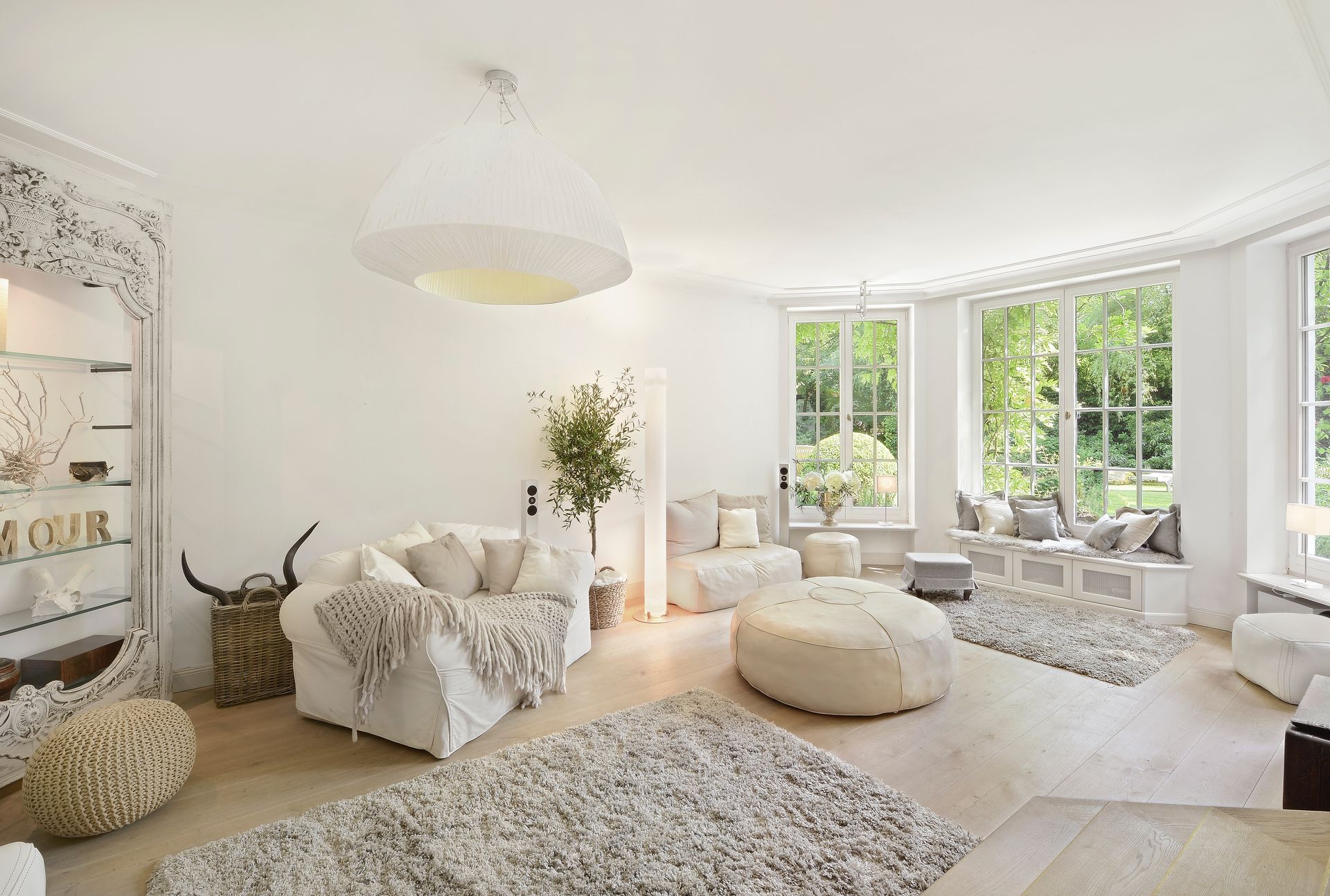 Bright white living room with plush seating, shag rugs, and large windows overlooking greenery