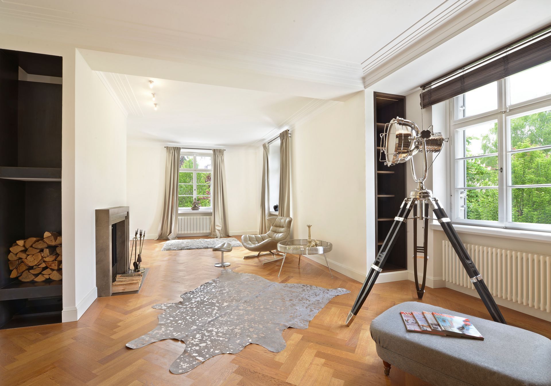 Bright living room with large windows, wooden floors, modern tripod camera, and scattered confetti on the floor