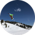Snowboarder midair over a snowy mountain slope under a blue sky.