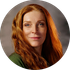 Portrait of a red-haired woman with a slight smile against a soft gray background