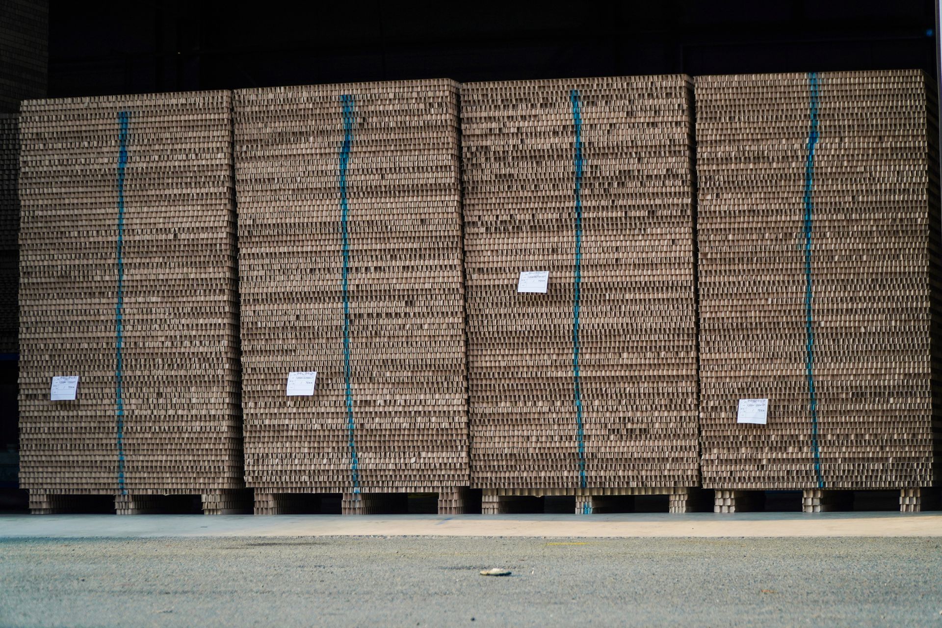 Neatly arranged stacks of corrugated cardboard sheets on wooden pallets in a warehouse. Neatly arranged stacks of corrugated cardboard sheets on wooden pallets in a warehouse.