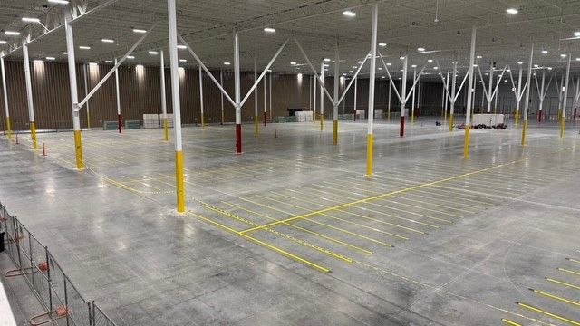 Empty warehouse interior with yellow floor markings and rows of white support columns