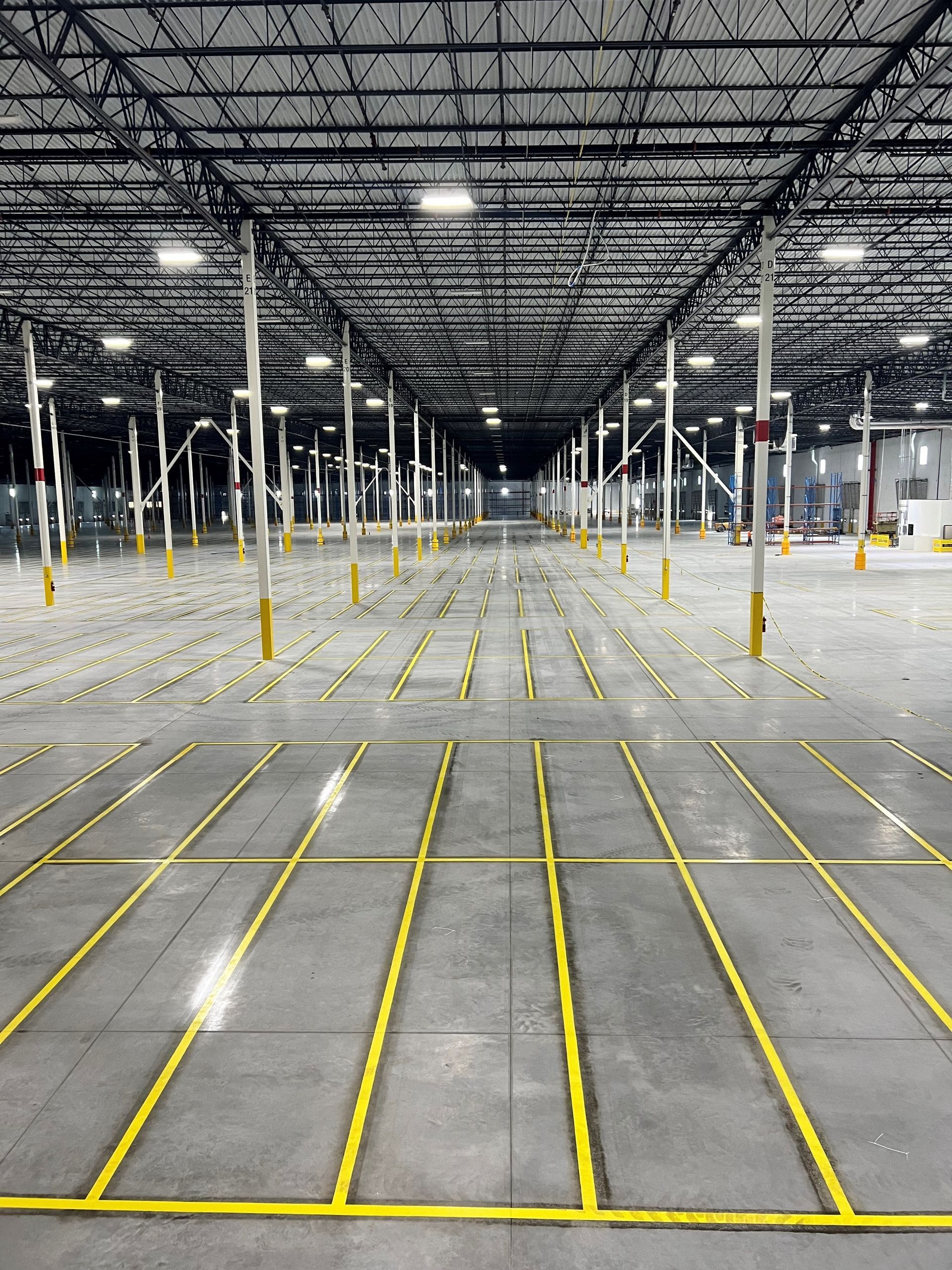 Empty warehouse interior with yellow floor markings and tall white support columns