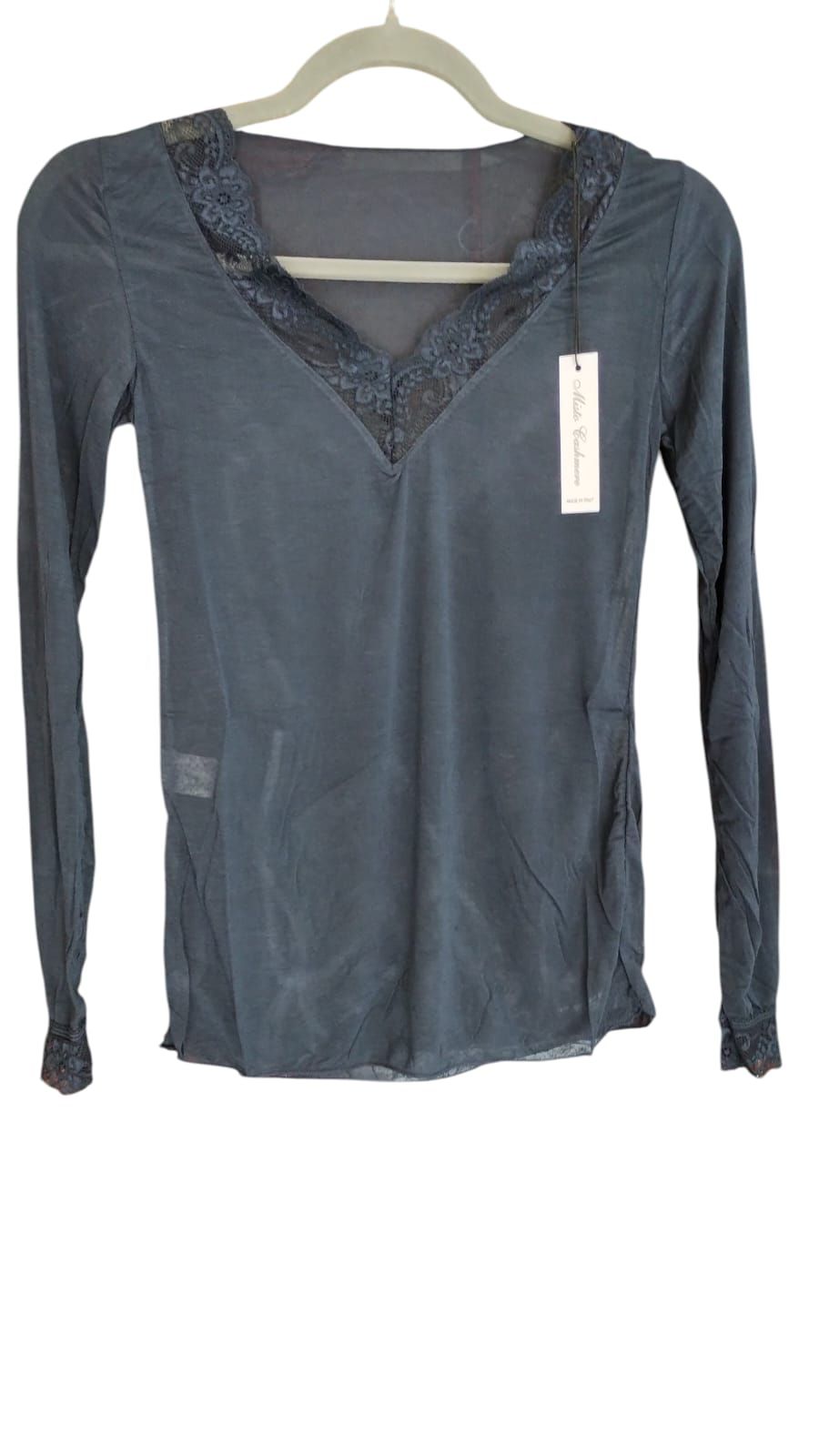 Mujer con blusa azul sosteniendo una bufanda azul transparente en una sala de estar luminosa.