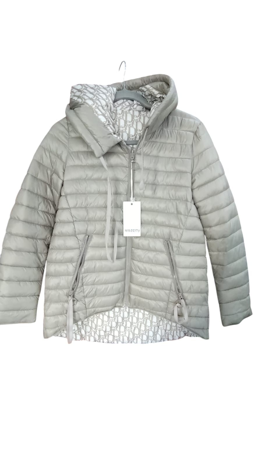 Una persona camina por un sendero pavimentado, vestida con una chaqueta acolchada gris claro.