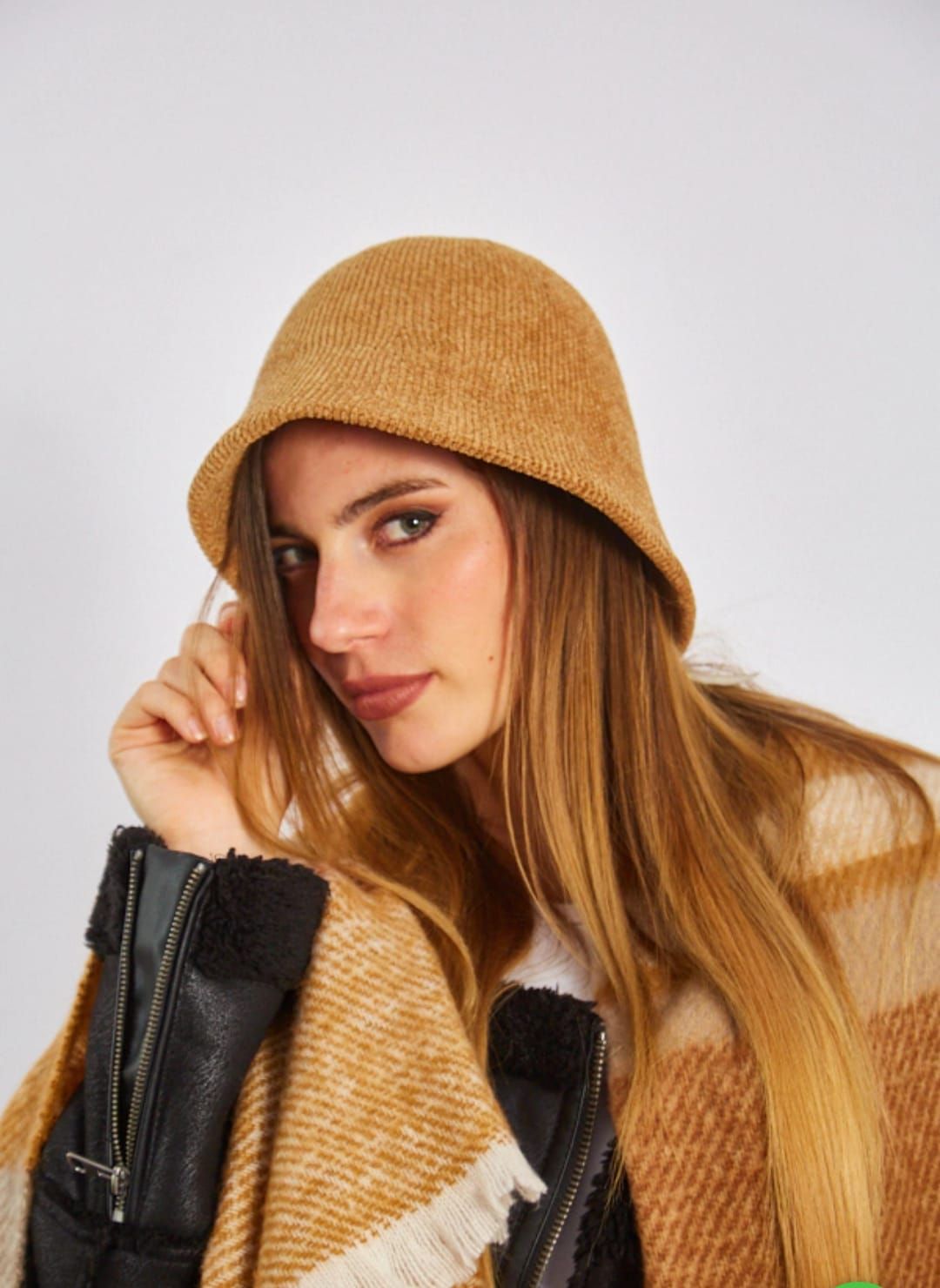 Mujer con sombrero negro y abrigo beige sobre una blusa con estampado de leopardo, posando frente a un fondo claro.