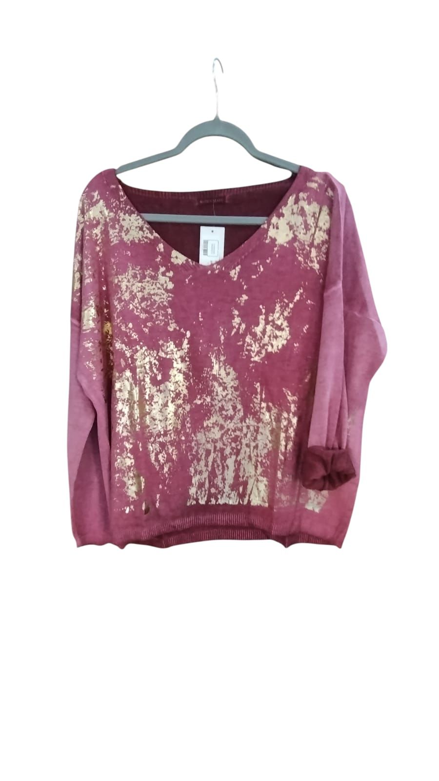 Mujer entrando en una oficina luminosa, sosteniendo una taza y vistiendo una blusa rosa y jeans.