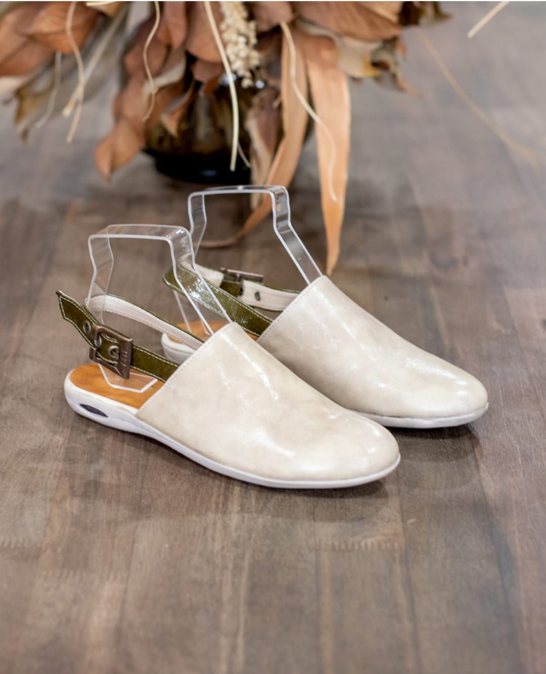 Botines transparentes con puntera blanca sobre un suelo de madera.