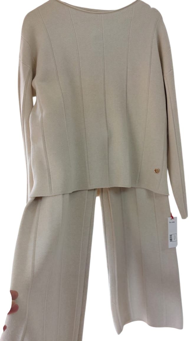 Top de punto beige de manga larga y pantalón ancho a juego colgados en una percha.