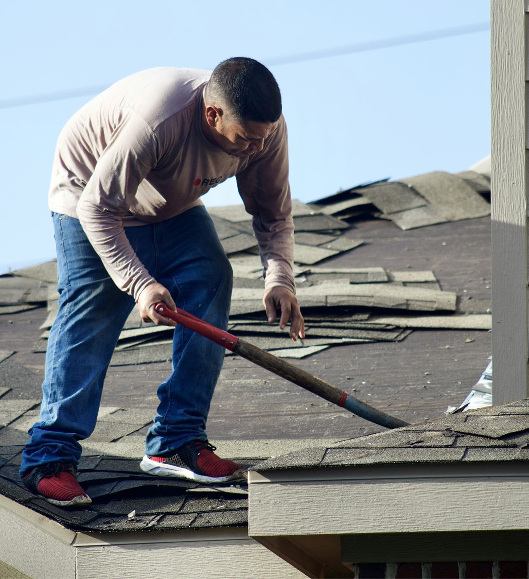 A man is working on a roof with a shovel