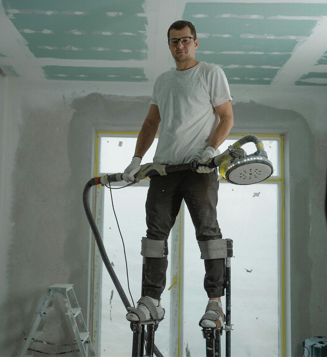 A man is standing on stilts holding a vacuum cleaner