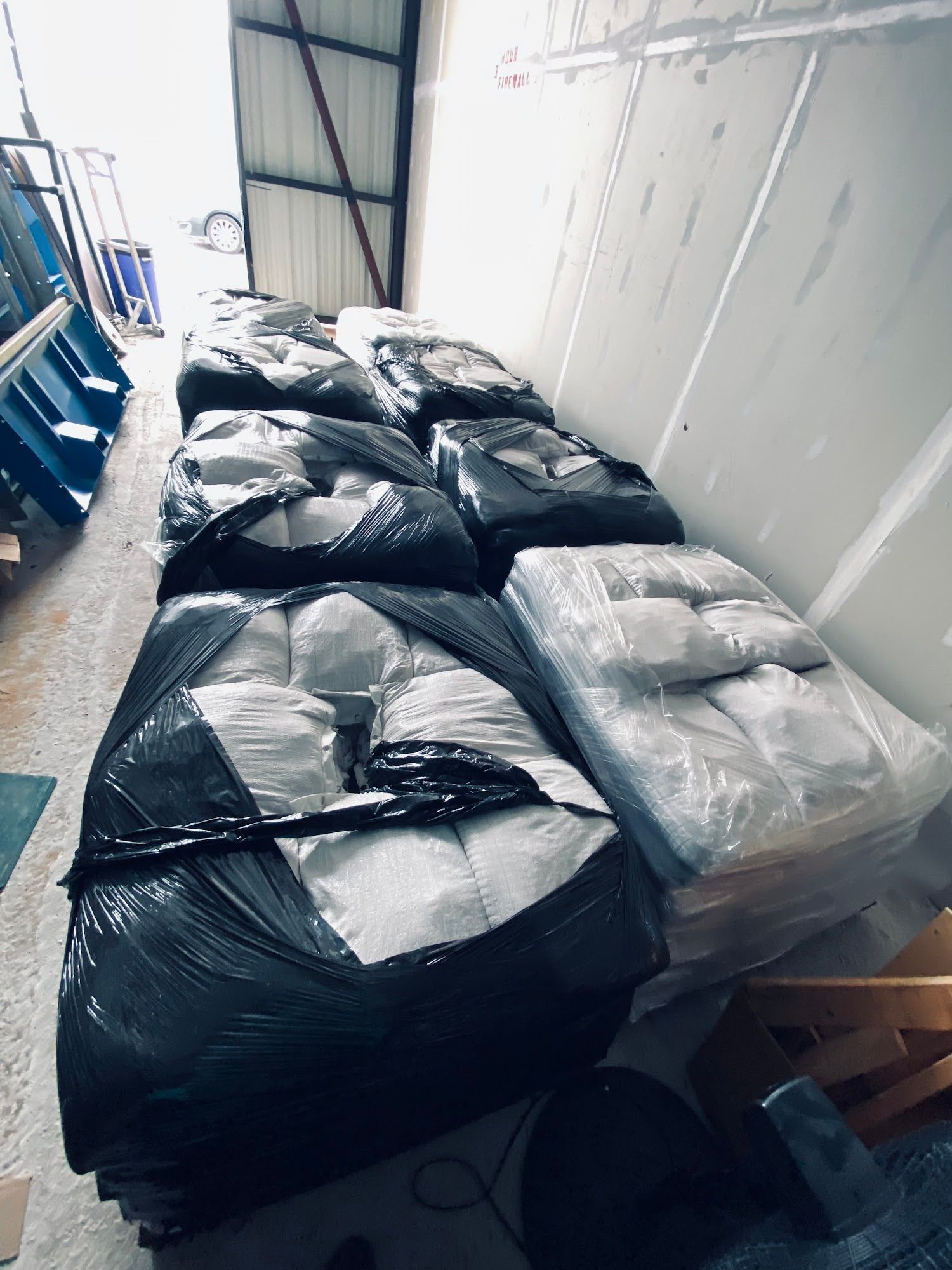 Rows of black and white bagged bundles stacked in a warehouse aisle