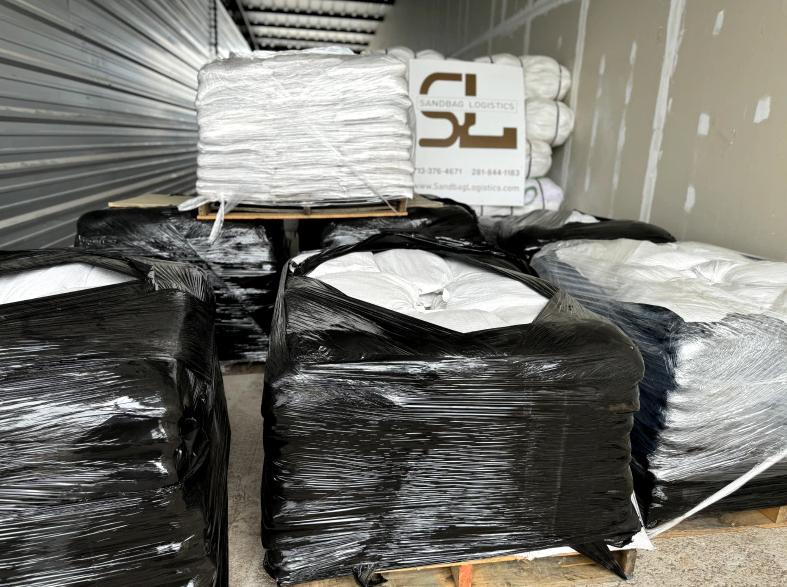 Packed black-wrapped goods stacked inside a cargo truck, with white packages on top.