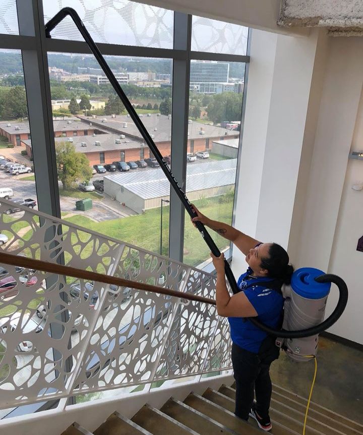 A woman is cleaning a window with a vacuum cleaner.