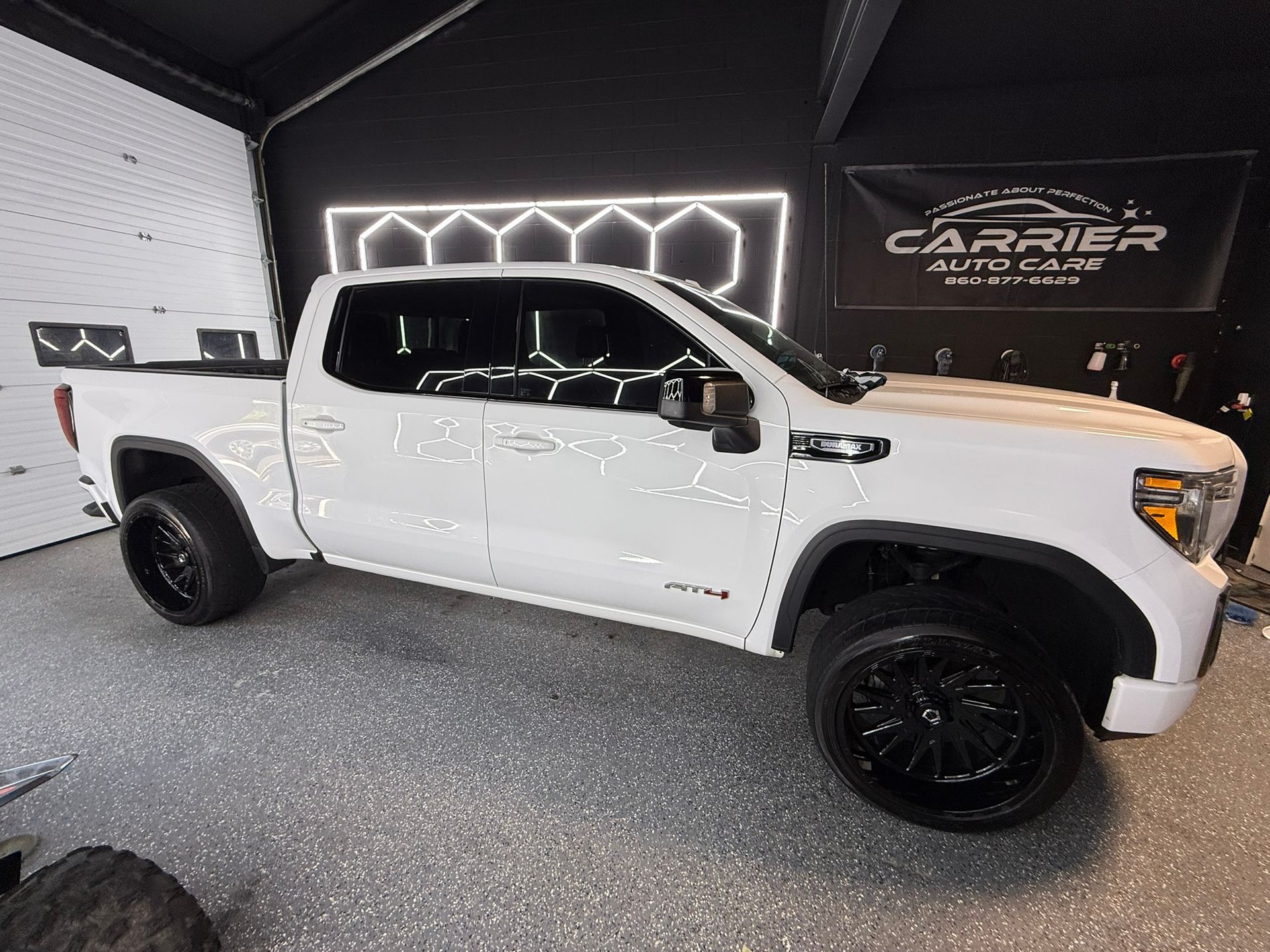 White GMC truck with black rims parked in a garage. 