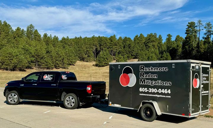 A truck is pulling a trailer. Black truck towing a trailer with
