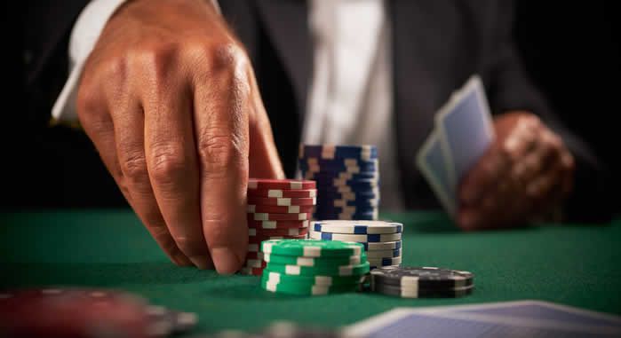 A man is playing poker with a pile of poker chips on a table.