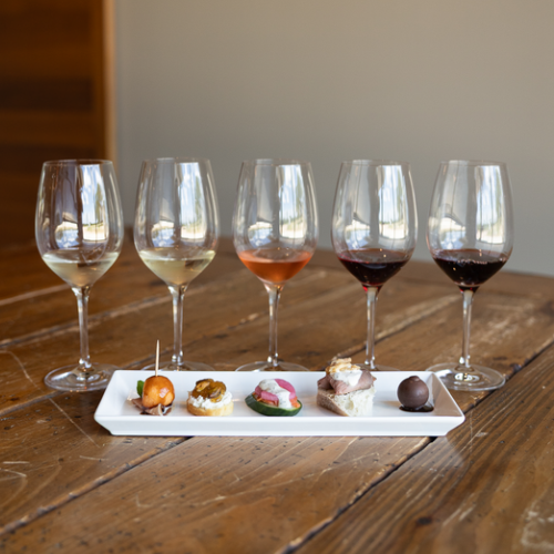 Wine glasses and bottles on a set dining table by a sunlit window