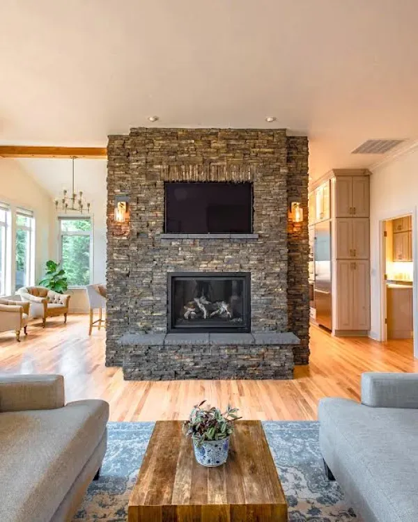 A living room with a stone fireplace and a flat screen tv