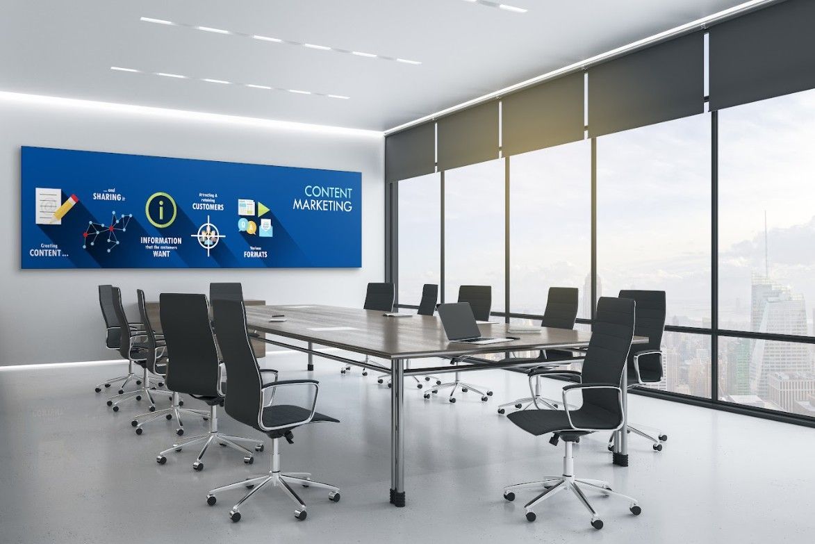 Modern office conference room with a large table, chairs, and a blue presentation board.