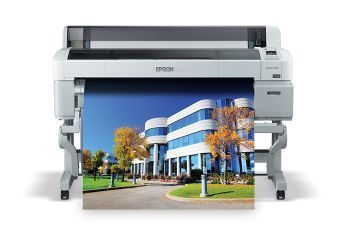 Hands feeding white paper into a large format printer.