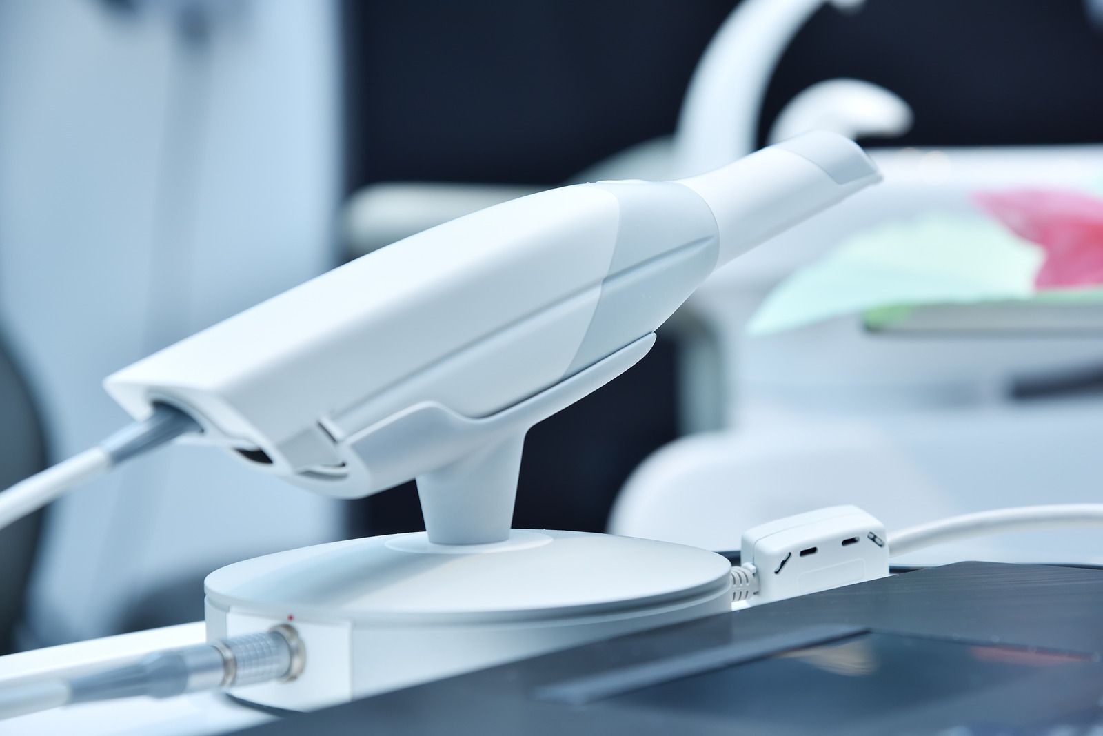 White intraoral scanner resting on its base in a dental office.