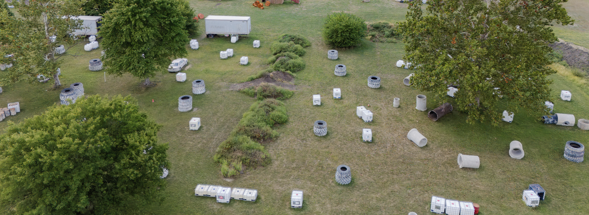 Aerial view of a field with trees and numerous beehives.