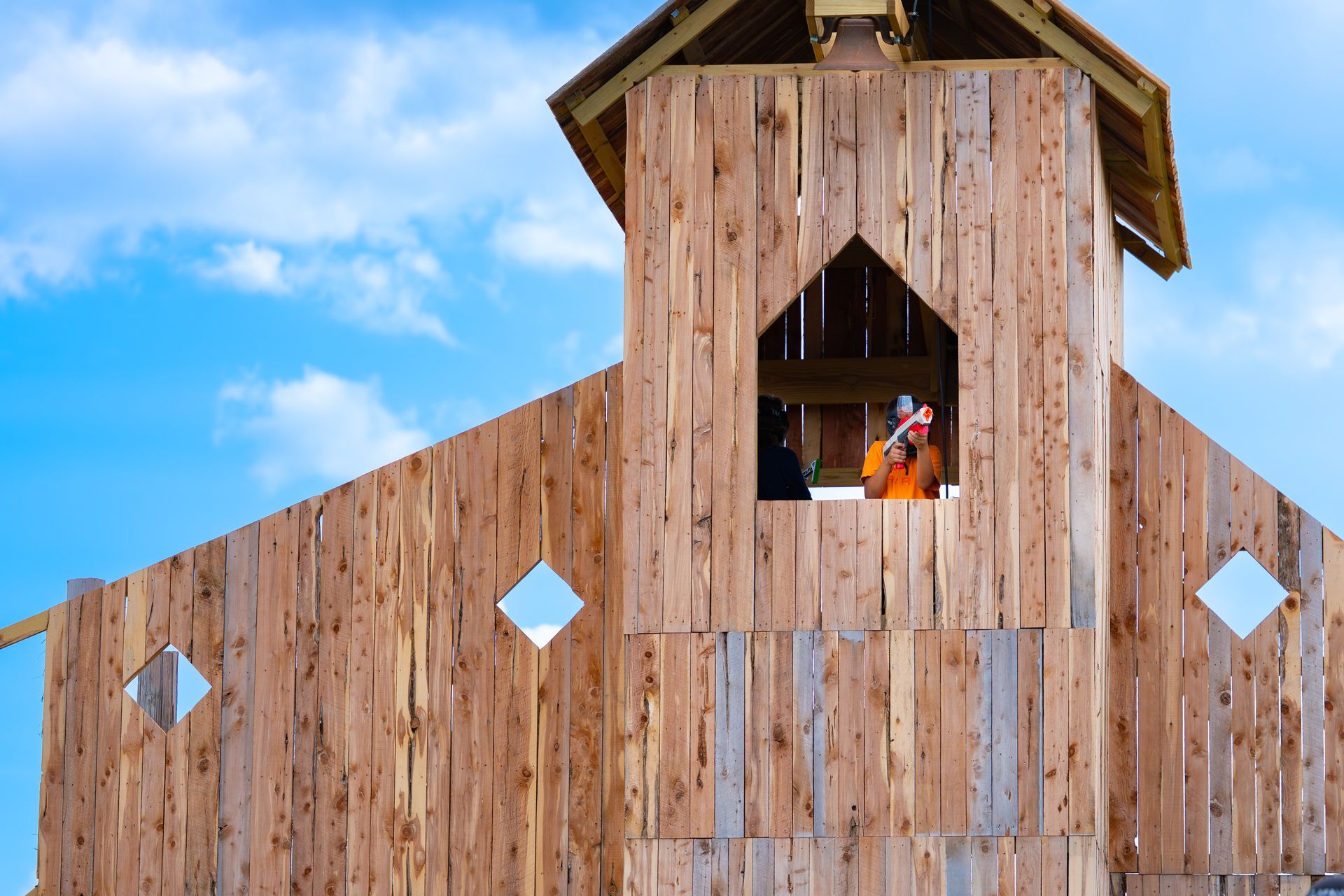 Wooden structure with person inside. Blue sky background.