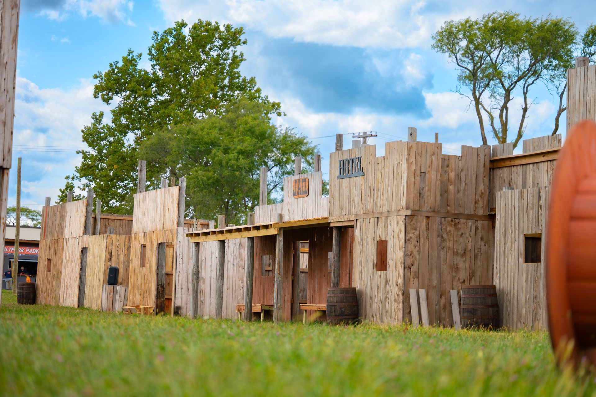 Wooden fort on green grass under a blue sky, with trees in the background.