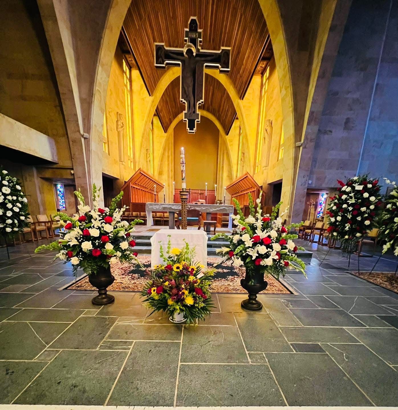 Church interior with altar, crucifix, and floral arrangements.