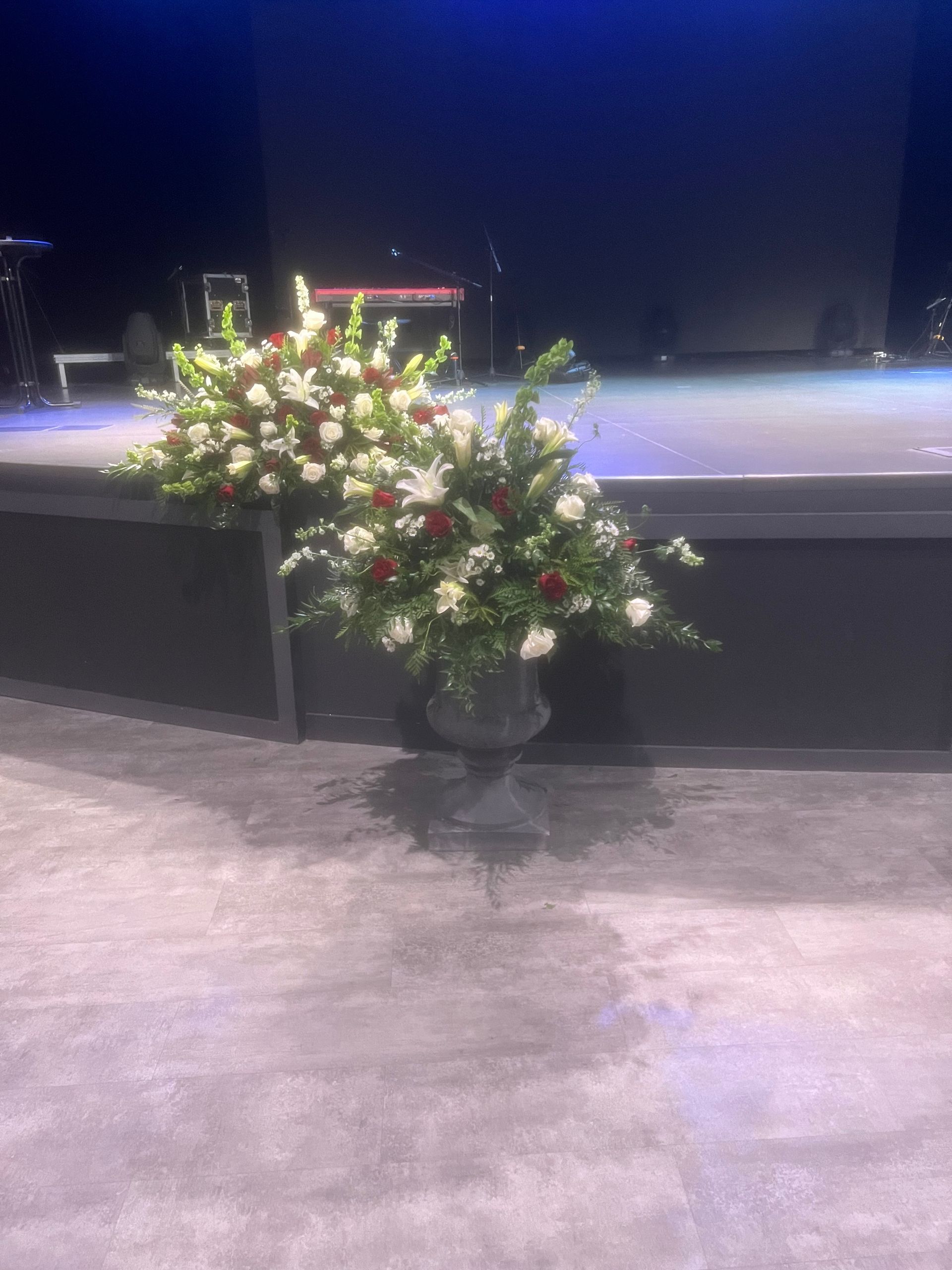 Urn with red and white flowers on a stage.