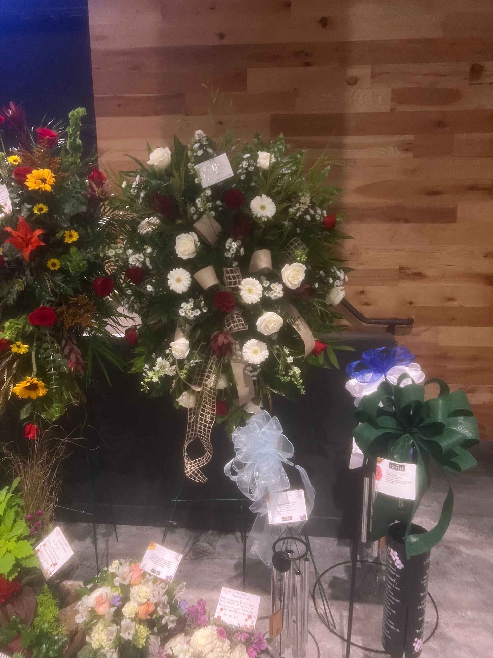 Floral wreath with white and red flowers, ribbons, on display in a store.