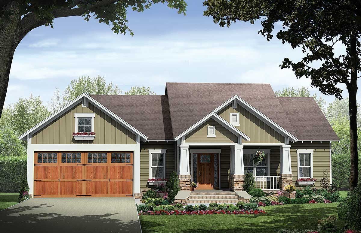 Cottage-style home with green siding, brown roof, and a wood garage door, surrounded by trees and landscaping.