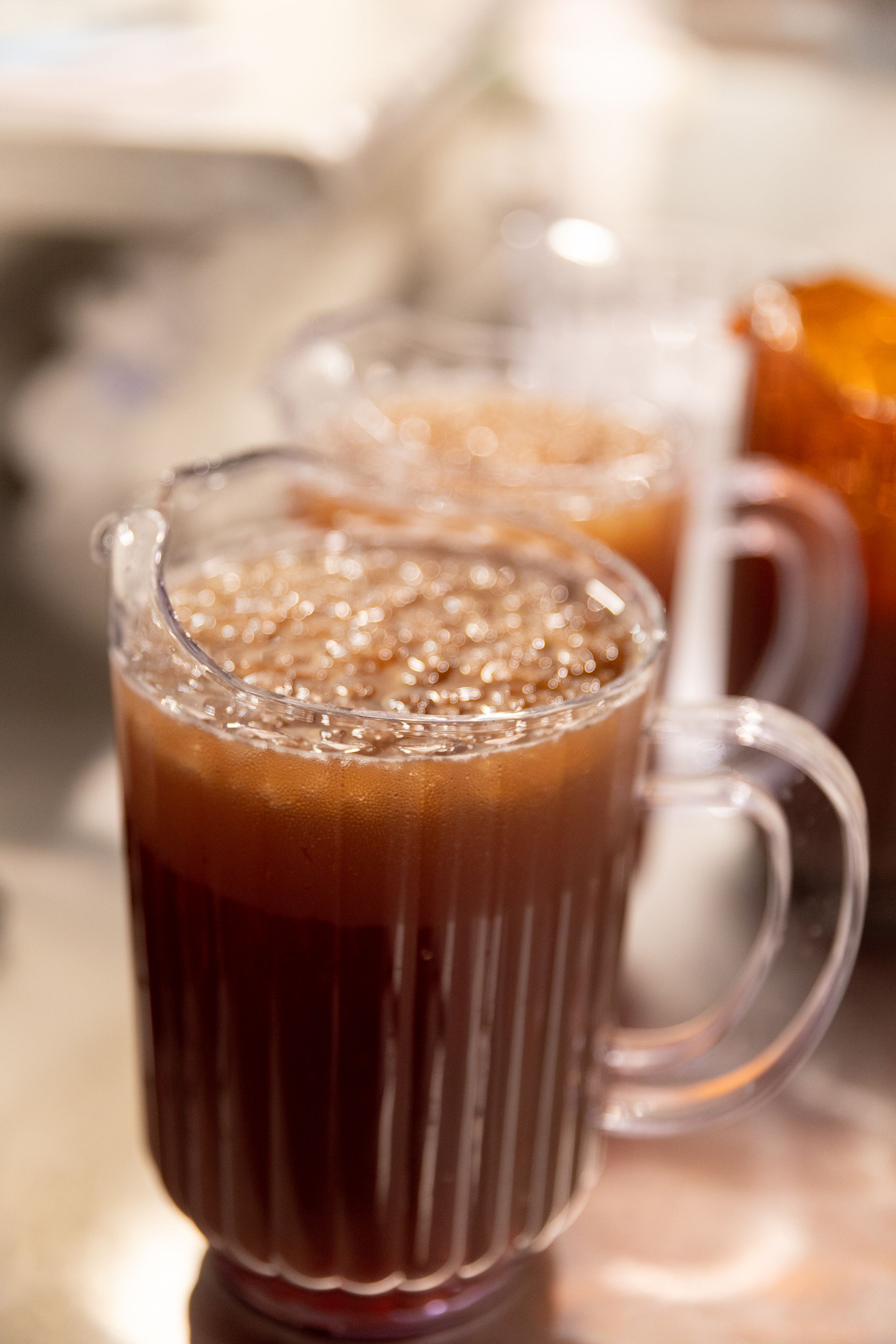 Three clear pitchers filled with brown liquid, possibly tea, with ice.