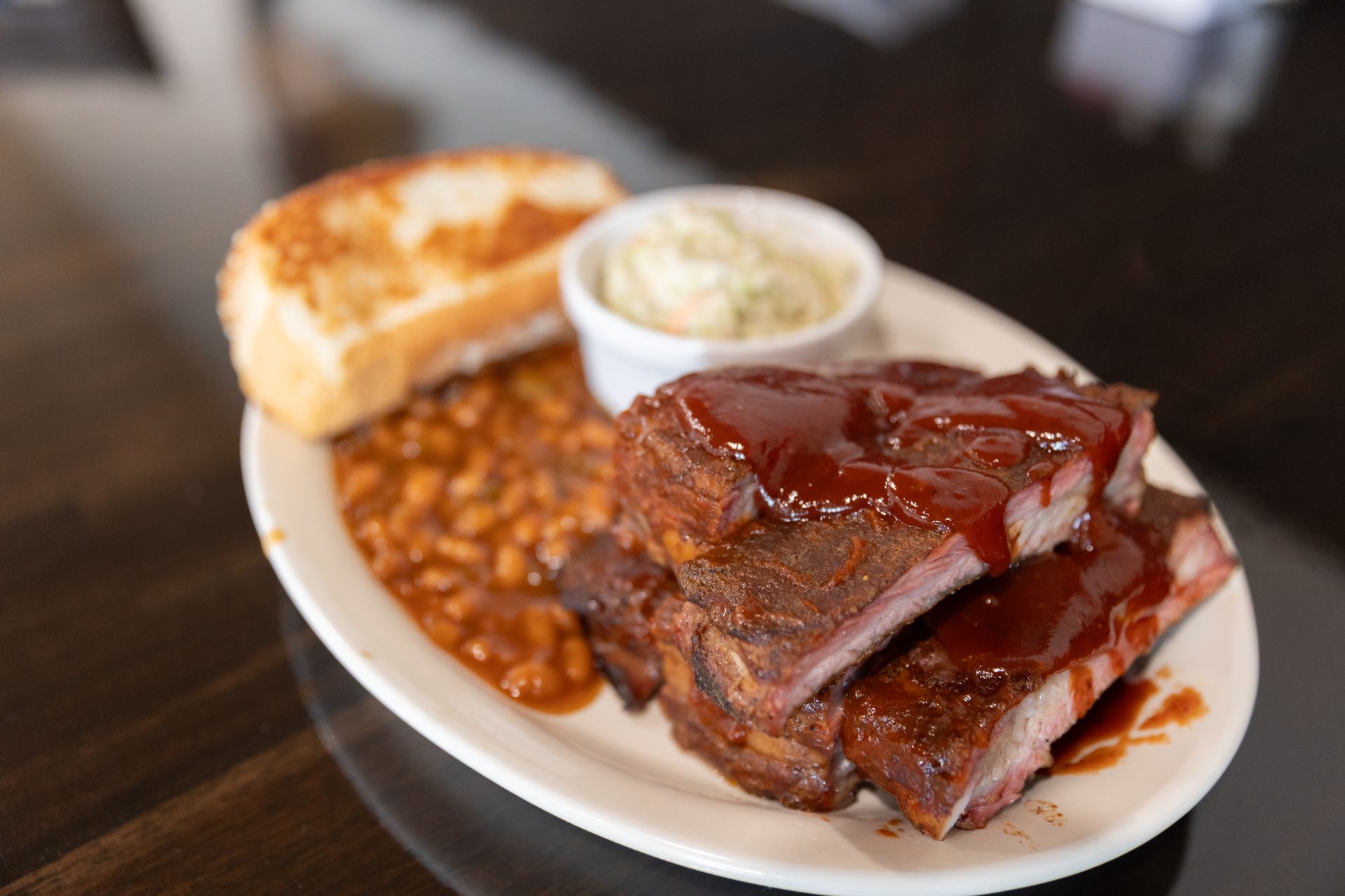 Plate of barbecue ribs, baked beans, coleslaw, and toast.