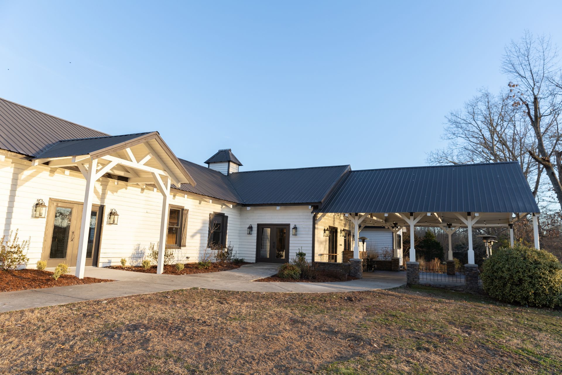 White building with black roof; covered porch area. Daytime.