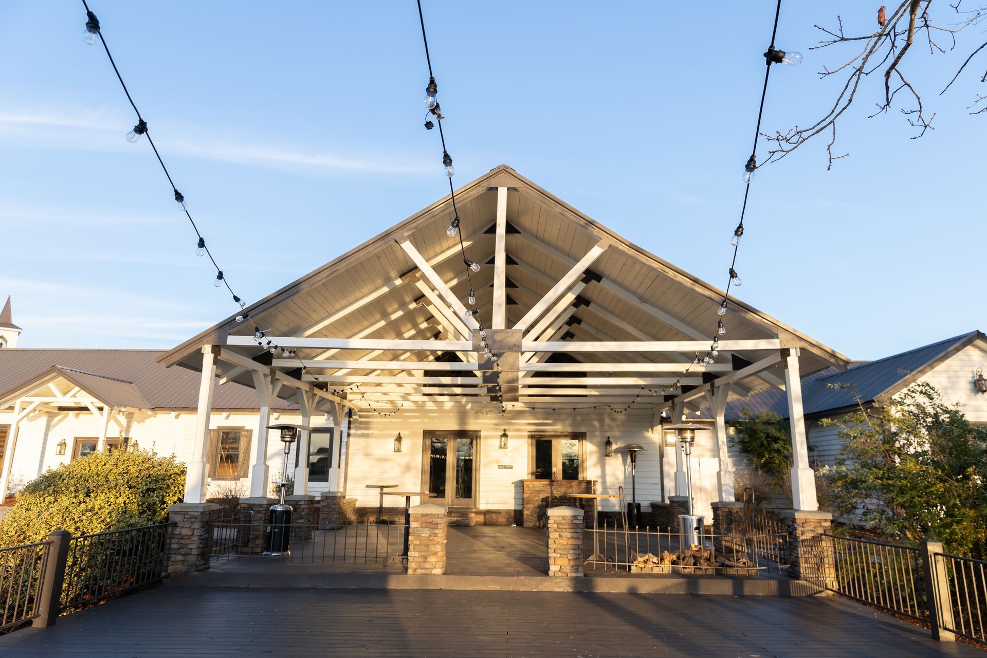 White building with covered patio and string lights.