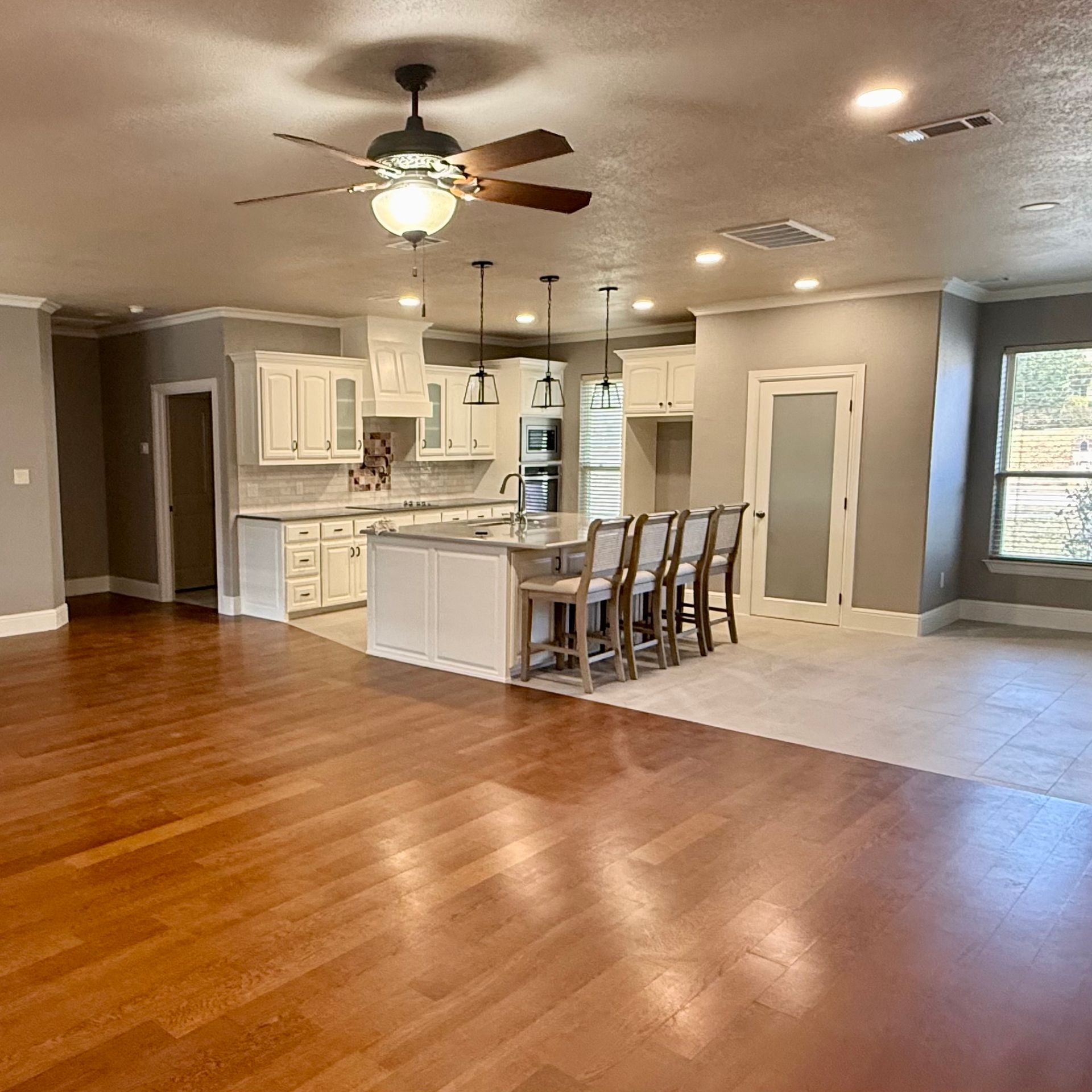 Spacious open-concept kitchen and living area with hardwood floors, island seating, and recessed lighting