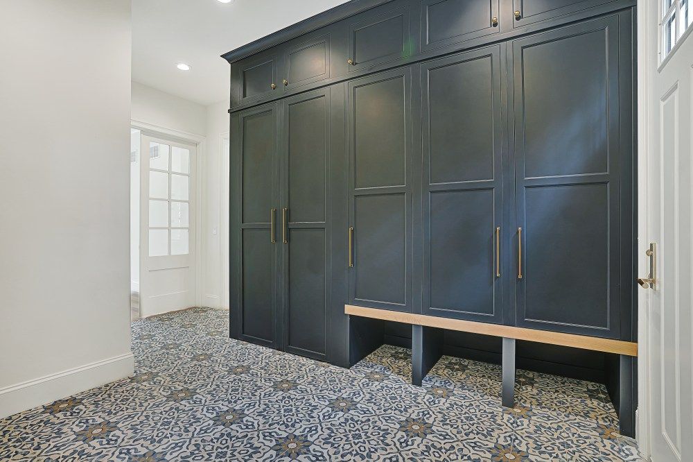 Built-in dark gray wardrobes in a bright room with patterned carpet and a small bench seat