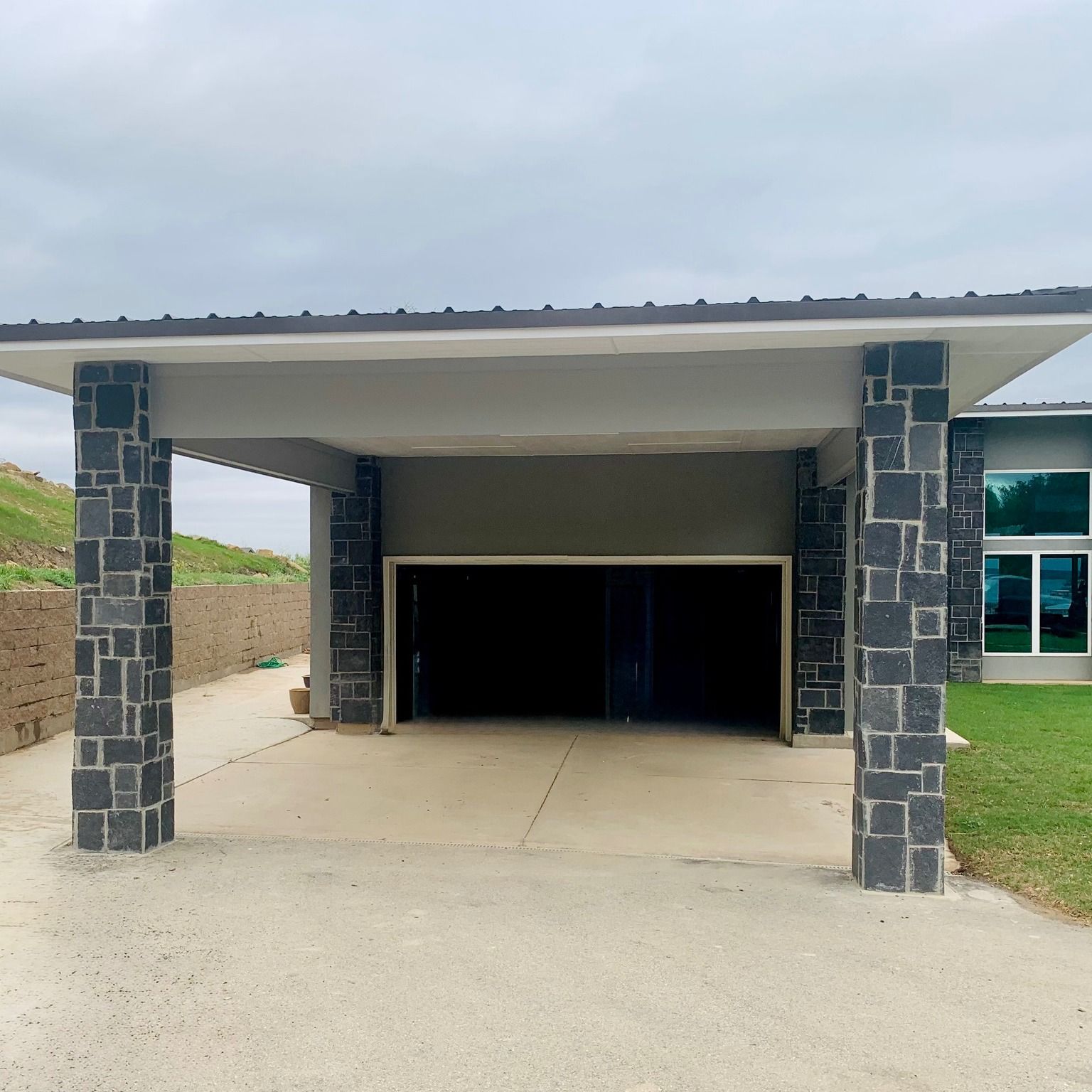 Covered driveway leading to a dark garage entrance on a modern house