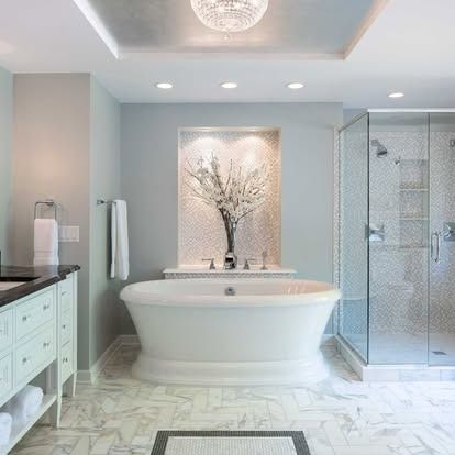 Bright white bathroom with freestanding tub, glass shower, vanity, and marble tile floors