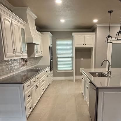 Bright modern kitchen with white cabinets, gray island, stainless appliances, and recessed lighting