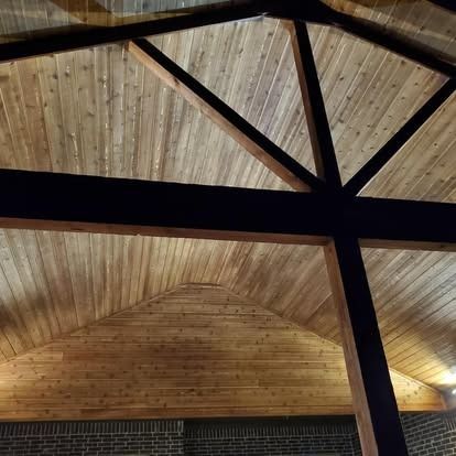 Wooden vaulted ceiling with dark exposed beams and a brick wall below