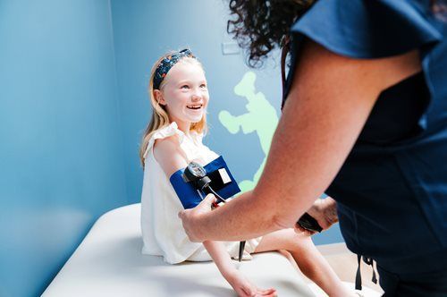 Dentist examining a smiling child in a bright clinic, holding dental tools near her mouth