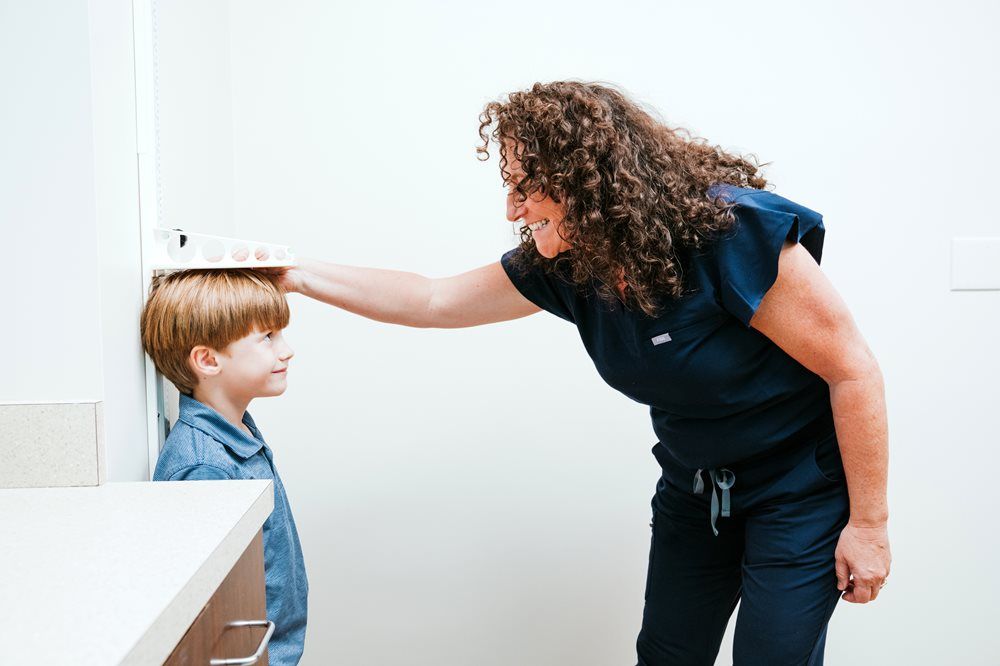 Woman measuring a child’s height with her hand in a bright room