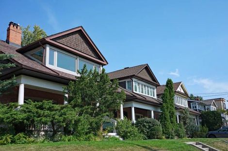 A row of houses with a car parked in front of them on a sunny day.