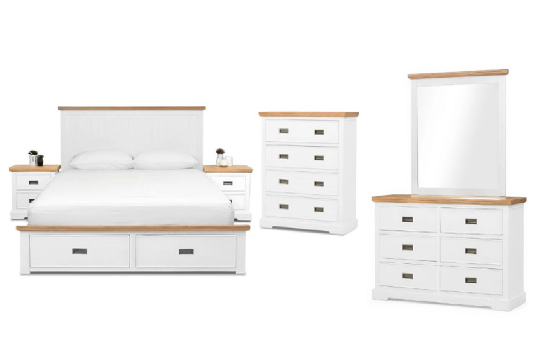 White bedroom furniture set against a dark blue wall. Includes a bed, dresser, nightstands, and chest.