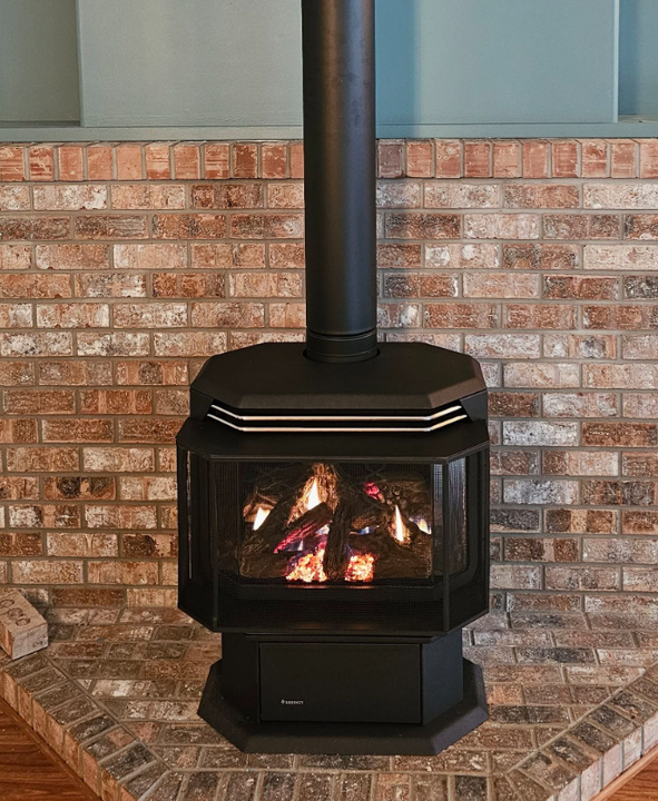 Freestanding gas fireplace against a brick wall